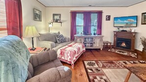 Un salon confortable avec un canapé, une table basse, une cheminée et un téléviseur.