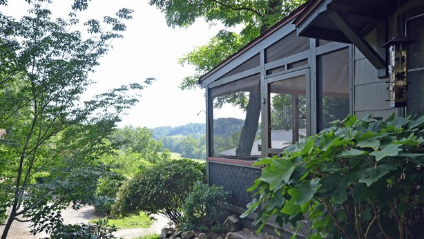 Une maison dotée d’une grande fenêtre donnant sur un paysage verdoyant et luxuriant.