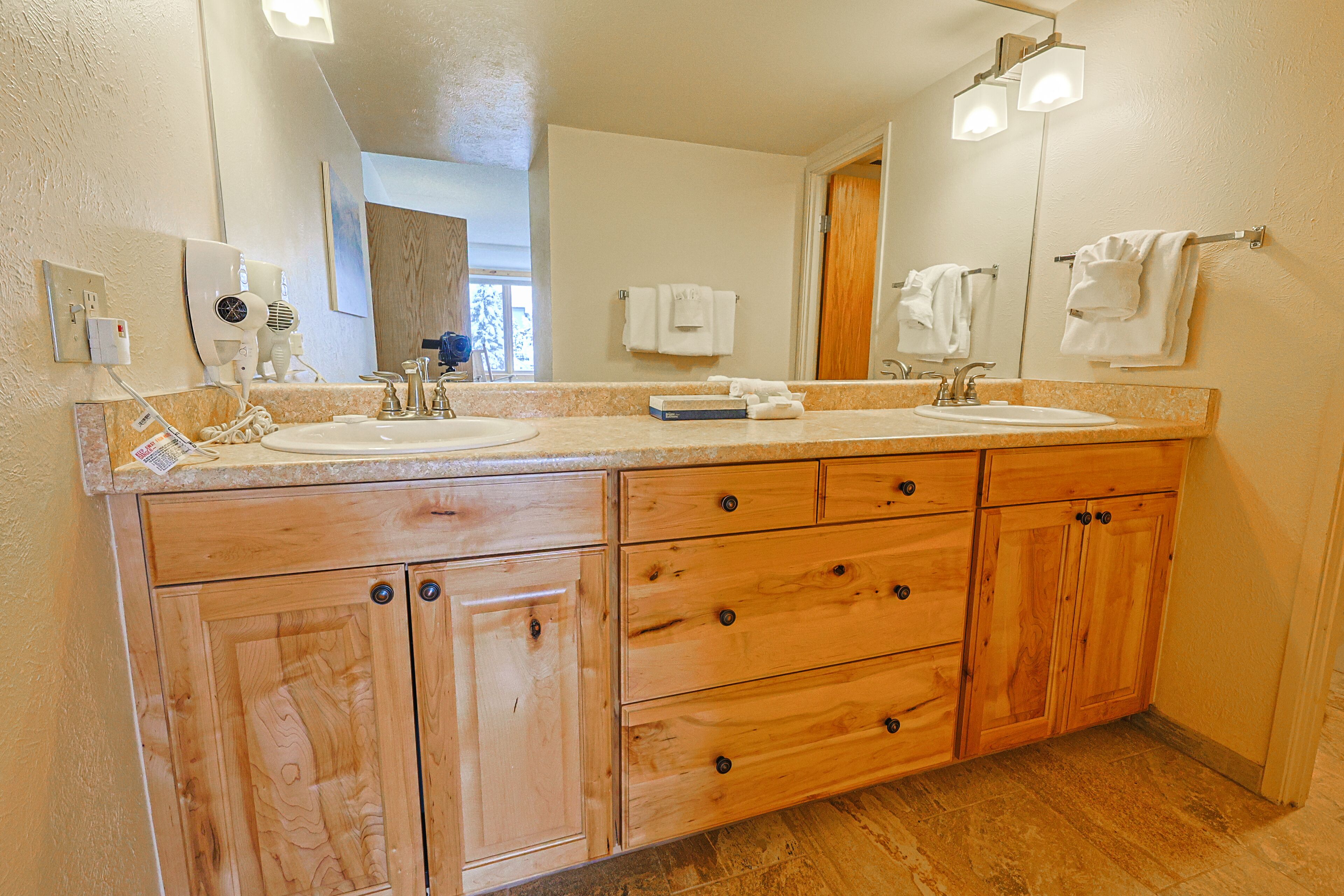 A bathroom with two sinks, wooden cabinets, and a large mirror.
