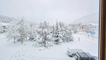 A snowy landscape with a road, parked vehicles, and snow-covered trees.