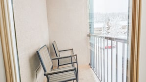 A balcony with two metal chairs and a glass railing overlooking a snowy landscape. - Summit House Short Walk to Skiing, Covered Parking Balcony w/ Panoramic Views (Copper Mountain)