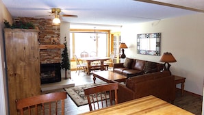 A cozy living room with a fireplace, wooden furniture, and a ceiling fan. - Summit House Short Walk to Skiing, Covered Parking Balcony w/ Panoramic Views (Copper Mountain)