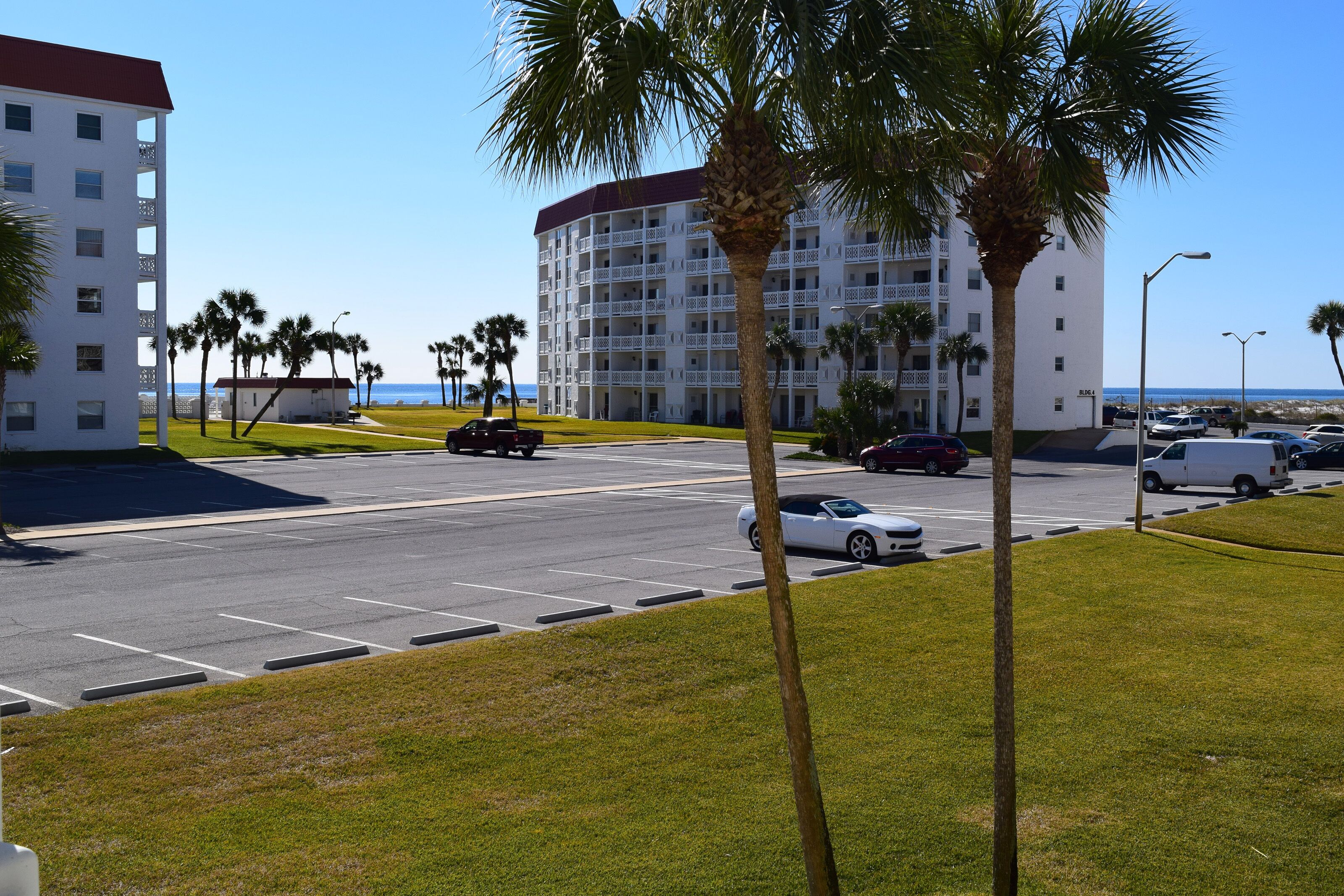 A hotel with multiple floors, a parking lot, and a view of the beach.