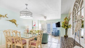 Zona pranzo con tavolo in vetro, sedie in legno e ventilatore a soffitto.