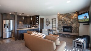 Una cocina moderna con electrodomésticos de acero inoxidable, una chimenea de piedra y un televisor de pantalla plana montado en la pared.