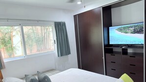 Ein Hotelzimmer mit Bett, Fernseher, Kleiderschrank und einem Fenster mit Vorhängen.