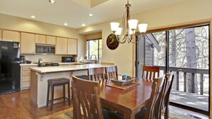 A modern kitchen with a central island, wooden dining table, and chairs.