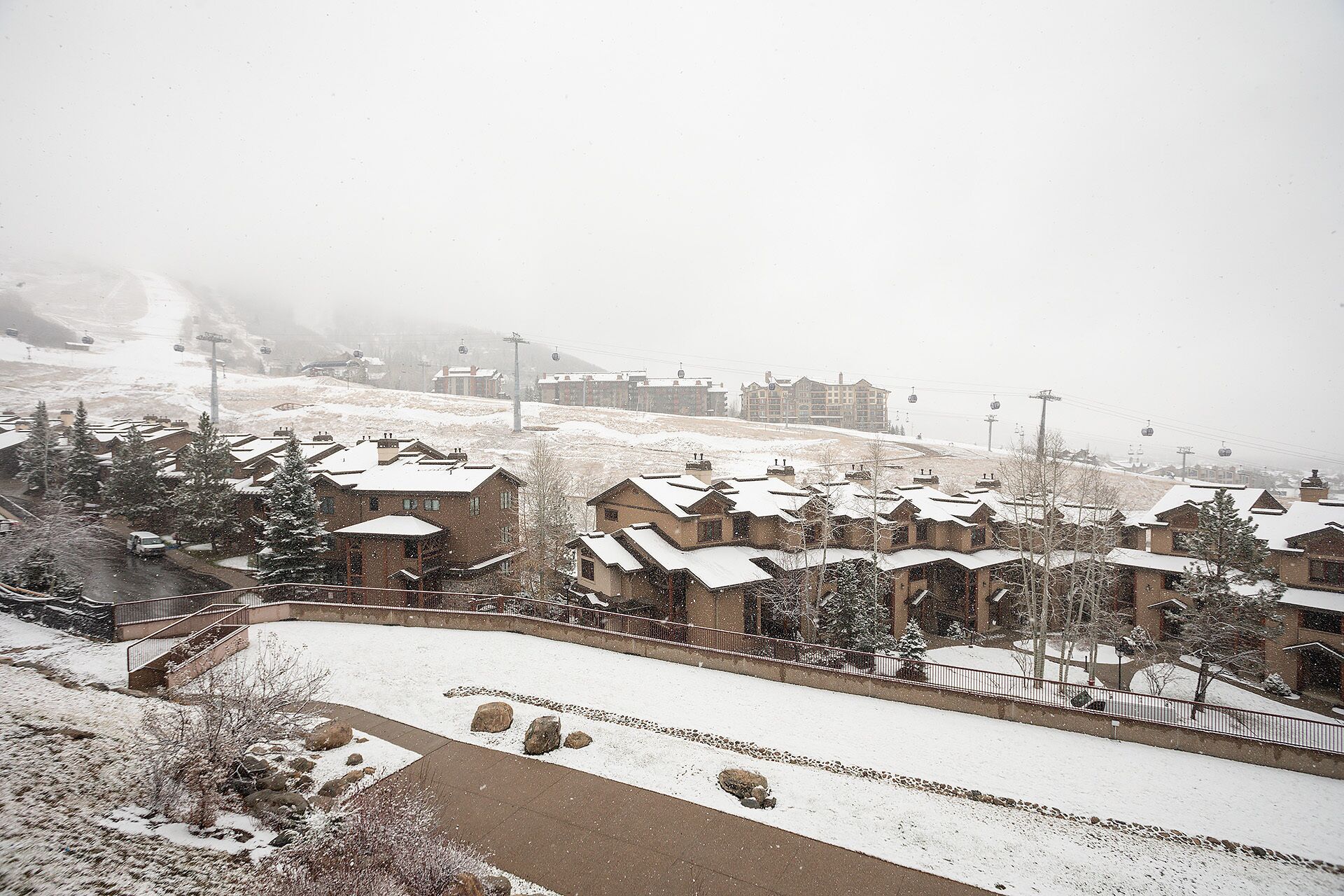 A snow-covered residential area with houses, a ski lift, and a mountain in the background.