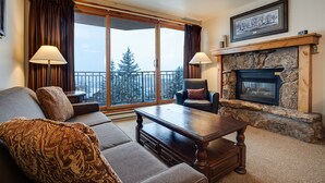 A cozy living room with a fireplace, a sofa, a chair, and a table. - BT304 | Remodeled Kitchen and Bathrooms | Walk to Base Area | Winter Shuttle (Steamboat Springs)