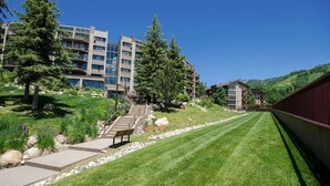 A modern hotel with multiple floors, outdoor seating, and a well-maintained lawn. - BT304 | Remodeled Kitchen and Bathrooms | Walk to Base Area | Winter Shuttle (Steamboat Springs)