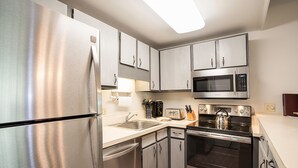 Una cocina moderna con electrodomésticos de acero inoxidable, que incluyen un refrigerador, un microondas y un horno.
