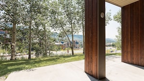 Ein überdachter Außenbereich mit Betonboden, Holzsäulen und Blick auf eine Straße sowie Gebäude im Hintergrund.