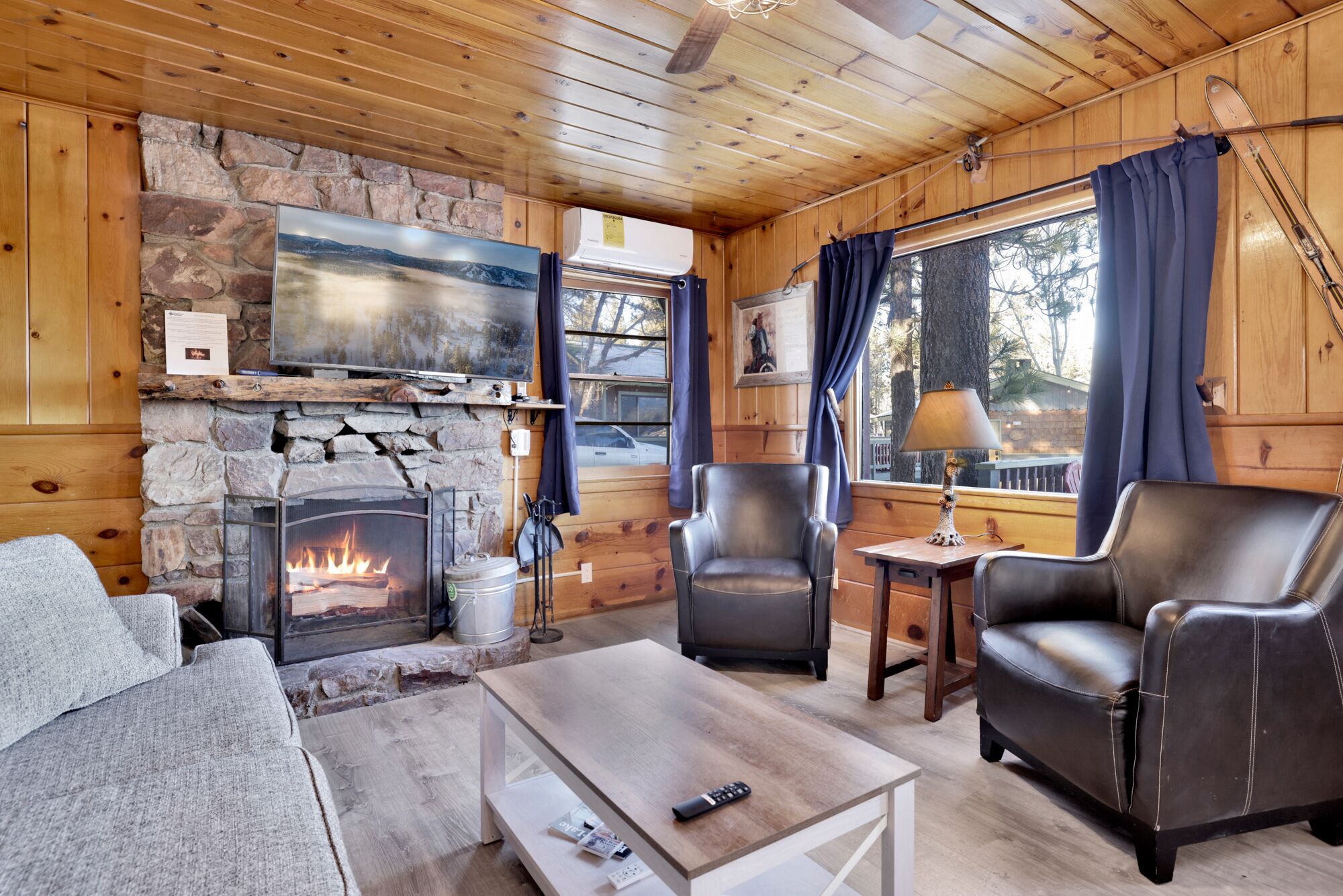 Cozy cabin living room with a stone fireplace, comfy seating, and rustic wood details—perfect for relaxing evenings, movie nights, and unforgettable mountain getaways.