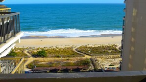 Une vue sur une plage, prise depuis un balcon, avec un océan bleu et une plage de sable.