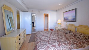 Une chambre à coucher avec un lit, une commode, un miroir et un tableau accroché au mur.