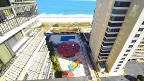 Un immeuble de grande hauteur doté d’une piscine sur le toit et offrant une vue sur la plage.