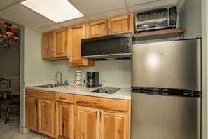 A kitchen with wooden cabinets, a stainless steel refrigerator, a microwave, and a coffee maker.