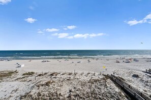 A wide sandy beach with a clear sky and calm sea.