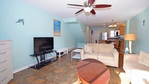 A living room with a flat-screen TV, a ceiling fan, a coffee table, and a sofa. - Crab Harbour 4-Baywater 28th St, W/D, AC (Ocean City)