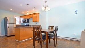 A modern kitchen with a central island, wooden chairs, and built-in appliances. - Crab Harbour 4-Baywater 28th St, W/D, AC (Ocean City)