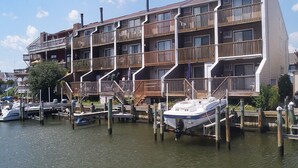 A multi-story building with balconies, docked boats, and a waterfront view. - Crab Harbour 4-Baywater 28th St, W/D, AC (Ocean City)