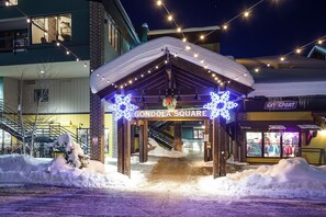 Une entrée enneigée donnant sur la place des gondoles, avec un abri en bois et des décorations en forme de flocons de neige.