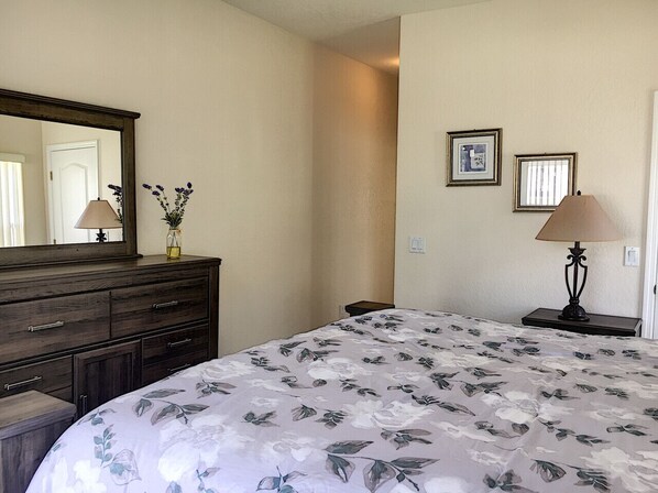 A bedroom with a bed, dresser, mirror, and two wall-mounted lamps.
