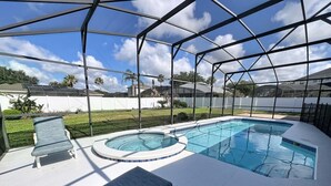 Une piscine extérieure couverte, dotée d’un jacuzzi, de chaises longues et offrant une vue sur les environs.