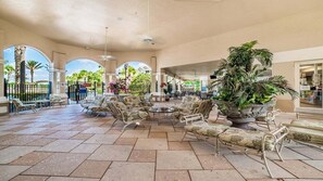 Relax in this spacious area with a high ceiling, surrounded by seating and lush greenery.