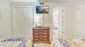 A hotel room with two beds, a dresser, a television mounted on the wall, and a view of a corridor. - three bedroom condo with loft, sleeps 8 (Gatlinburg)