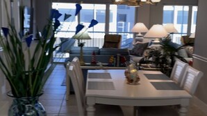 A dining area with a white table, chairs, and a vase of green plants. - Bright And Beachy (Sanibel)