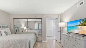 Une chambre avec deux lits, une télévision et vue sur la plage.