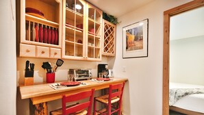 A compact kitchen with wooden cabinets, a dining table, and red chairs. - Managed by Park City Lodging-One Block to Park City Mtn's Quit'N Time Ski Run (PARK CITY)