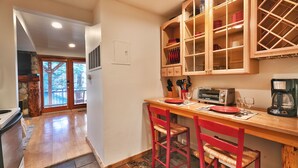 A kitchen with wooden cabinets, a dining table, and red chairs. - Managed by Park City Lodging-One Block to Park City Mtn's Quit'N Time Ski Run (PARK CITY)