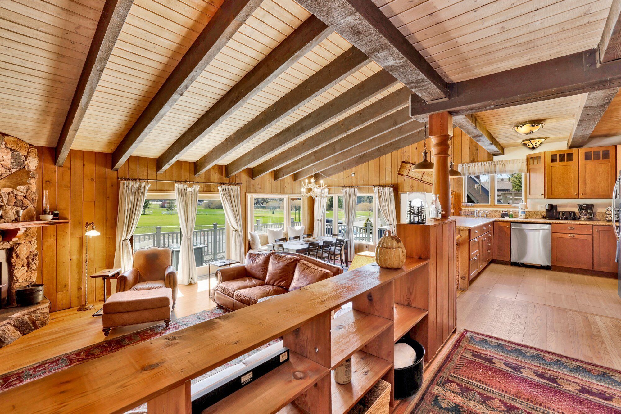 Cozy mountain living room with wood ceilings, stone fireplace, comfy seating, and smart TV—perfect for relaxing evenings, movie nights, and warm cabin vibes after outdoor adventures.