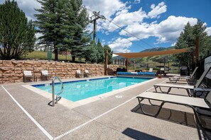 A swimming pool with lounge chairs and a stone wall.