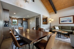 A spacious living area with a wooden dining table, leather chairs, a sofa, and a coffee table.