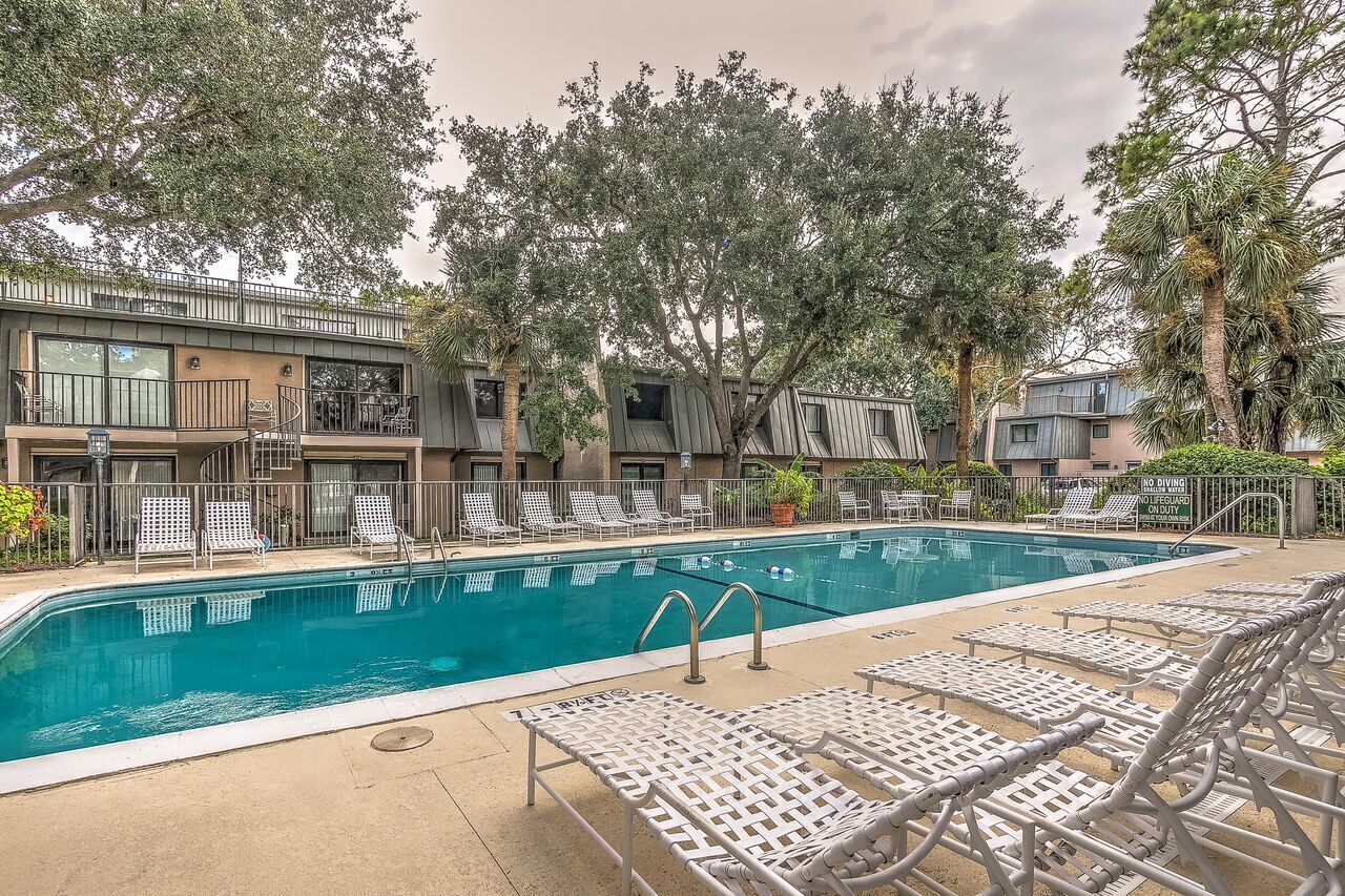 A swimming pool with lounge chairs and a building with balconies.