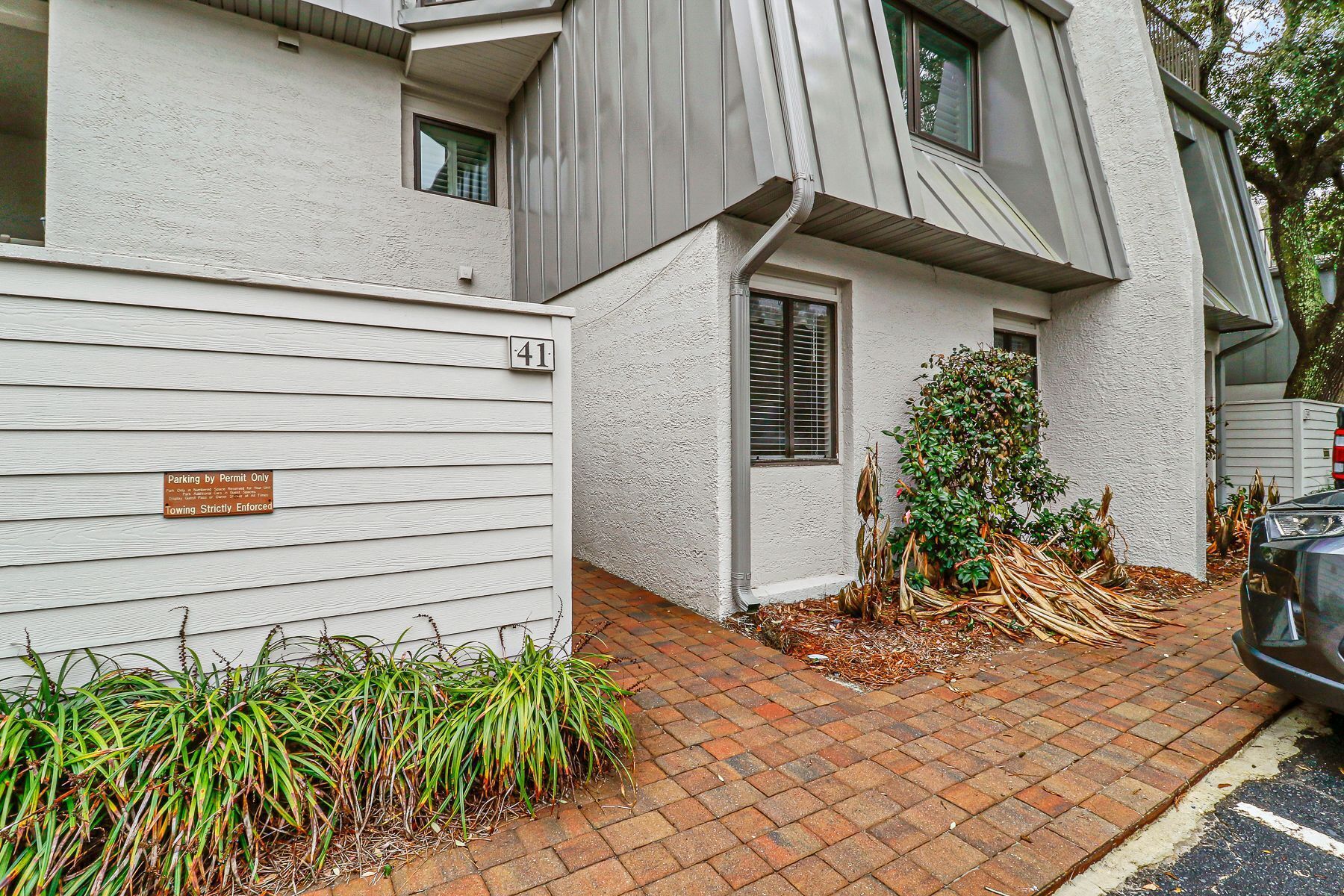 A residential building with a white exterior, a number 41 sign, and a driveway leading to a parked car.