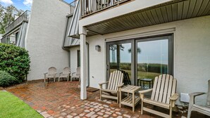 A patio with outdoor seating and a glass door leading to a deck. - Stunning Oceanfront Retreat. Steps to the sand and Coligny! (Hilton Head)
