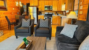 Un intérieur de chalet chaleureux comprenant un coin repas, une cuisine et un espace détente avec des coussins à motifs.