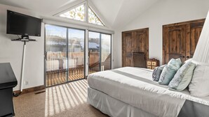 Ein Schlafzimmer mit einem großen Bett, einem Fernseher, einem Deckenventilator und einer Glastür zum Balkon.