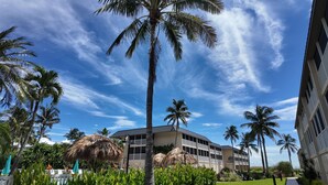 A hotel with a large building, palm trees, and a clear blue sky. - WHATA VIEW! (Sanibel)