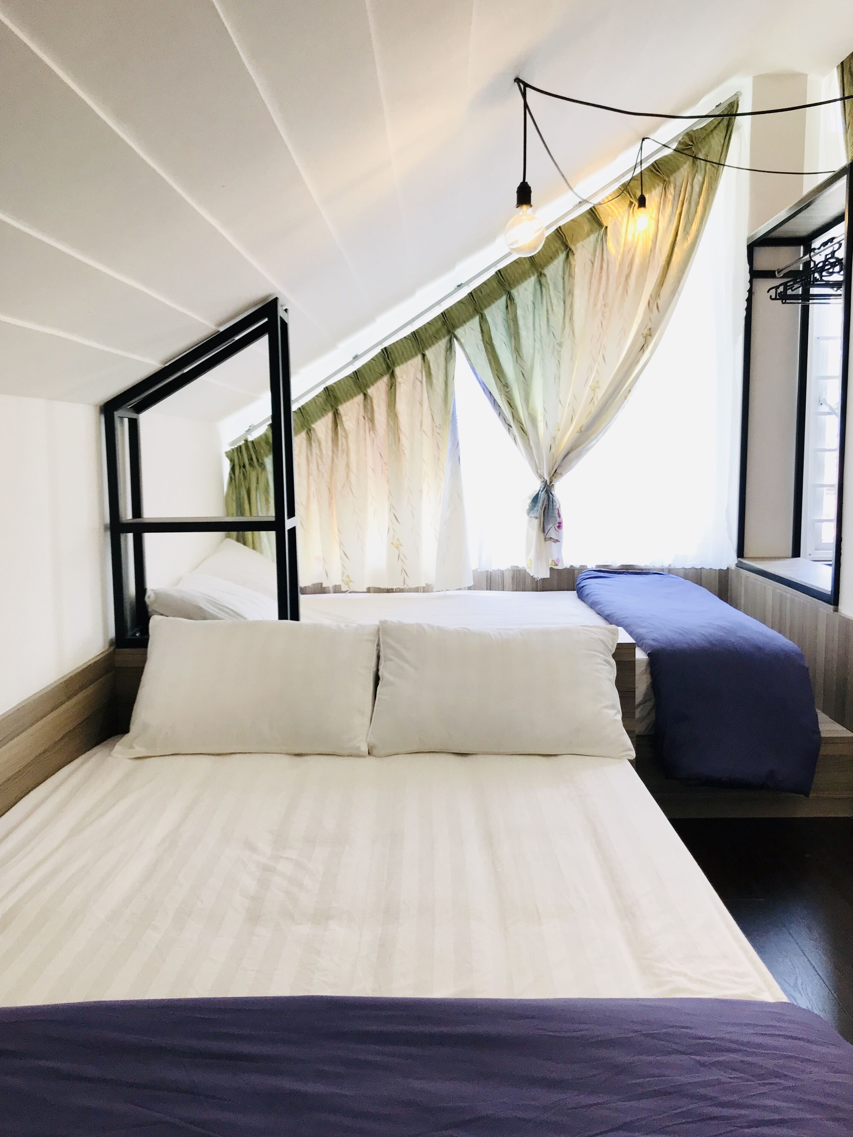 Una stanza con un letto, una finestra con tende e un lampadario.