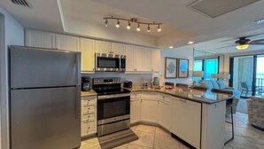 A modern kitchen with stainless steel appliances, white cabinetry, and a large island.