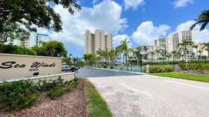 A paved pathway leading to a building labeled "Sea Winds 890" with a clear sky and tall buildings in the background.