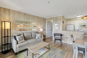 Uma sala de estar moderna com sofá, mesa de centro e um espaço de jantar com cadeira e mesa.