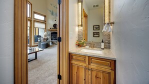 A bathroom with a stone accent wall, a large mirror, and a wooden vanity.
