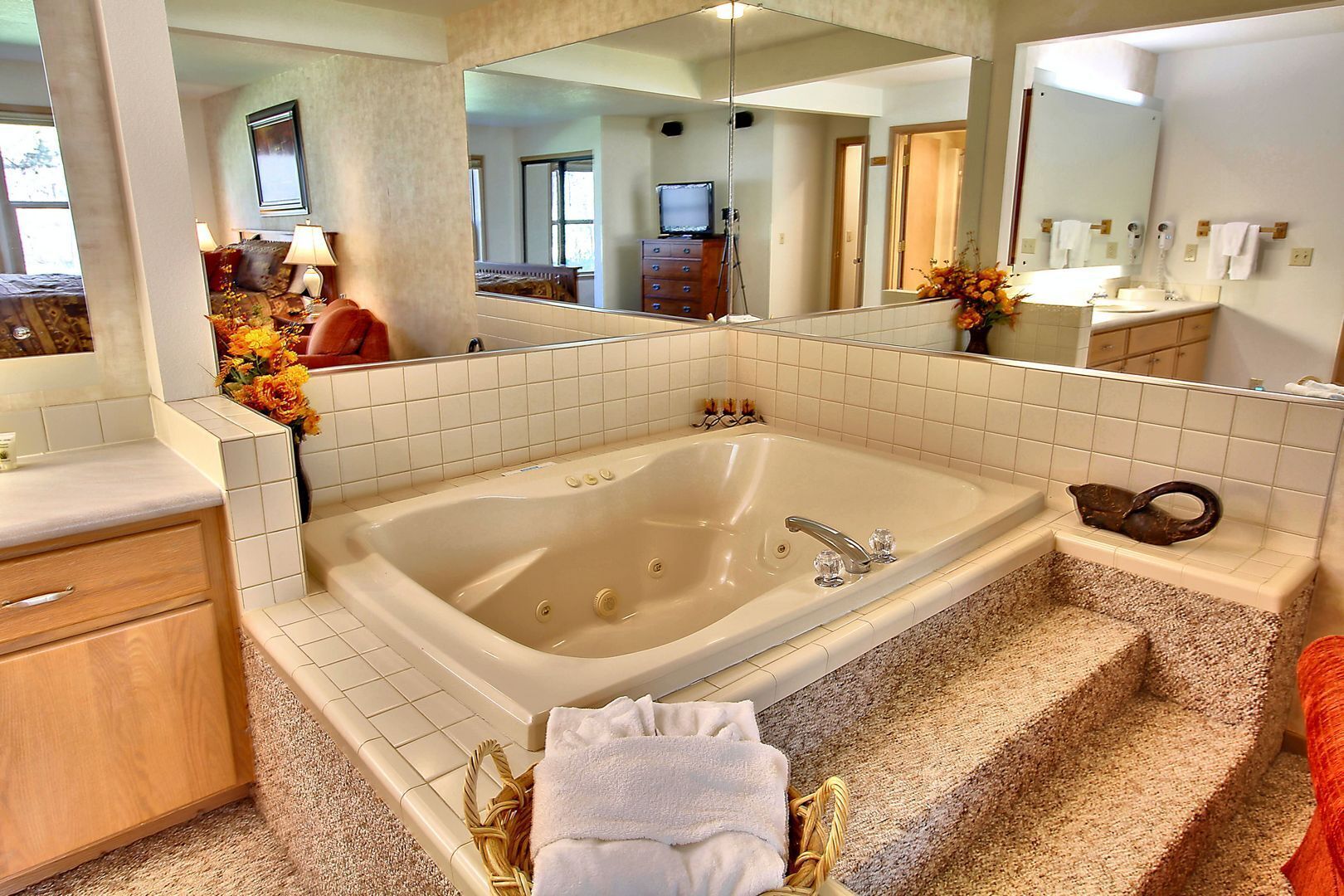 A bathroom with a large bathtub, a vanity with a mirror, and a sink.