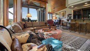A spacious living area with a large sofa, a coffee table, and a bar area with stools.